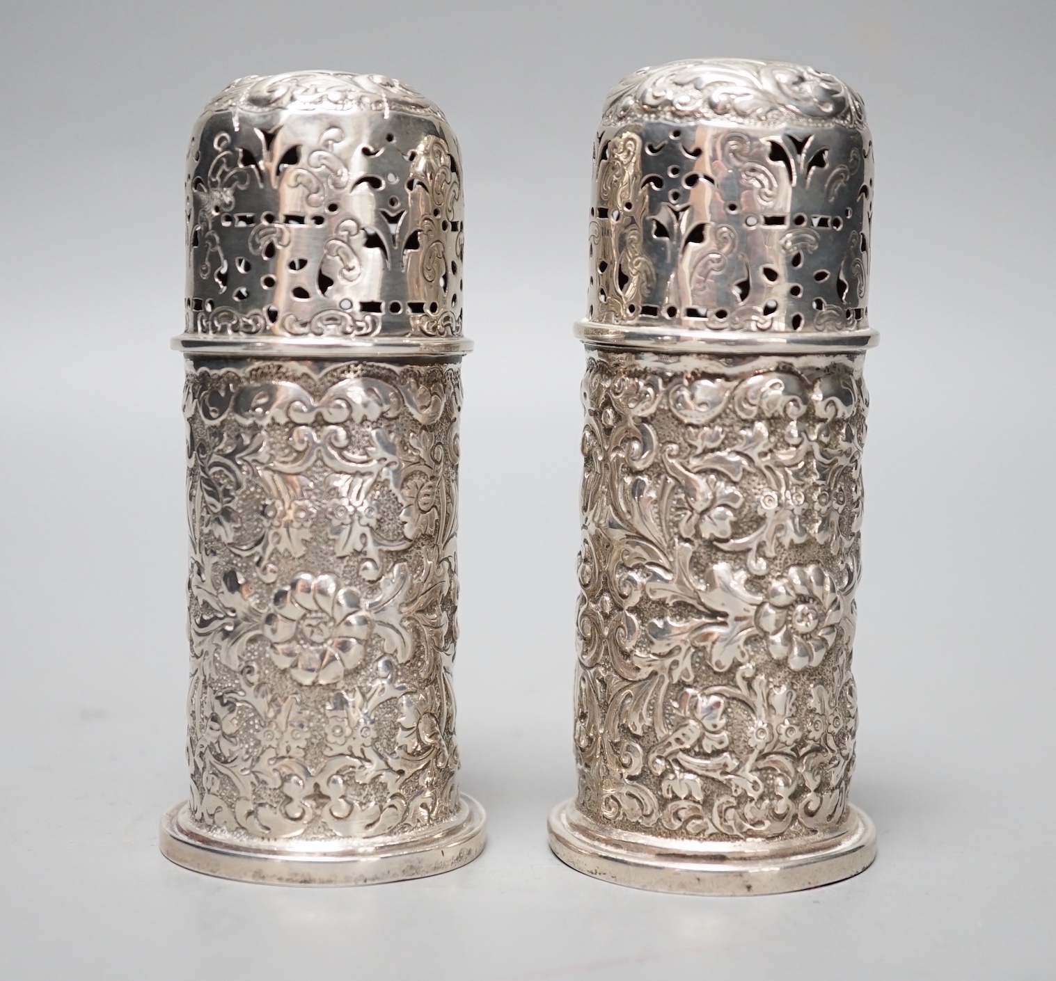 A pair of late Victorian embossed silver small lighthouse pepperettes, Horace Woodward & Co, London, 1895, 10.3cm, 156 grams.